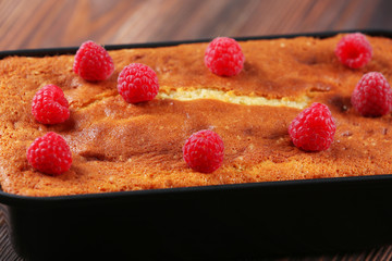 Fresh pie with raspberry in pan on wooden table, closeup