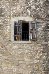 Fototapeta na wymiar building made of natural stone with a window and half-open shutt