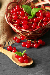 Ripe red currant in wicker basket on wooden background