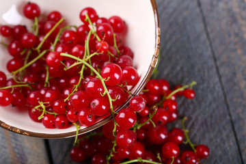 Fresh red currants in bowl on wooden table close up