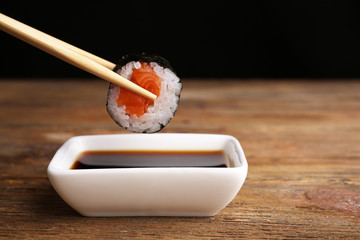 Dipping roll in sauce on dark background