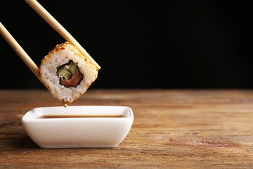 Dipping roll in sauce on dark background