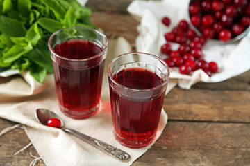 Two glasses with cherry juice on table, on wooden background