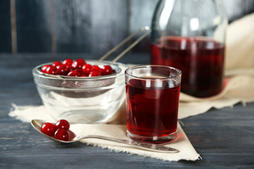 Sweet homemade cherry juice on table, on color wooden background