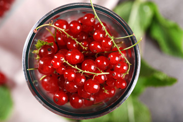 Ripe red currants in glass on table, top view