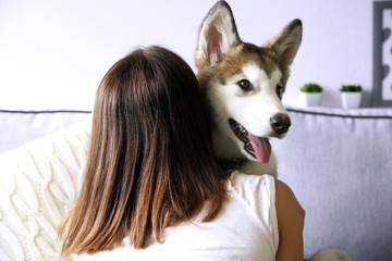 Woman hugging malamute dog in room