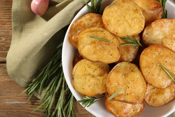 Naklejka na ściany i meble Delicious baked potato with rosemary in bowl on table close up