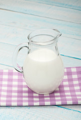 Obraz na płótnie Canvas jug of milk on a purple checkered tablecloth