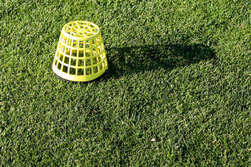 Empty yellow plastic bucket at a golf course driving range