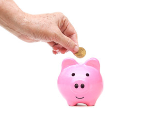 old female elderly hand putting a golden coin into a saving piggy bank - saving money for retirement concept