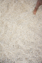 Sand on beach with one foot