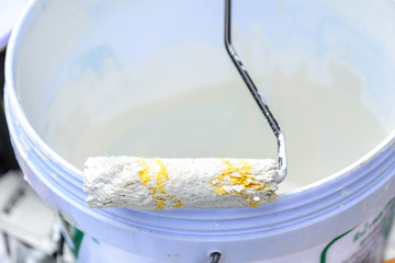 White color in bucket for paint wall with paint roller.