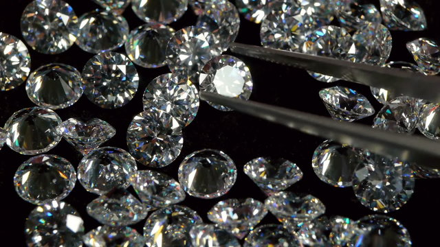 Selecting a Clear White Diamond With Pincers. 