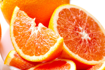 juicy sliced red oranges close-up on white plate 