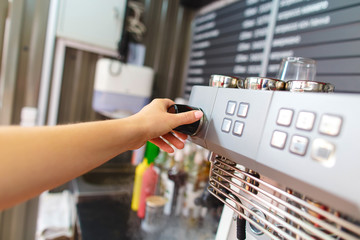 Selected focus on the hands of professional barista pushing the button