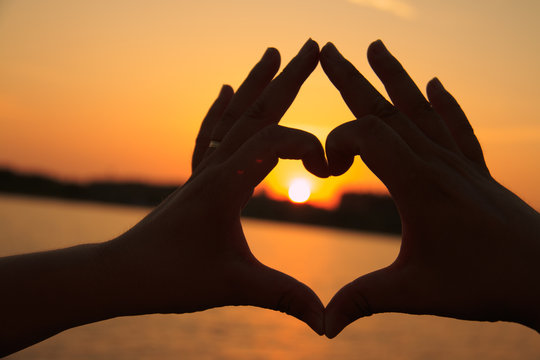 Heart-shaped hand against the sunset