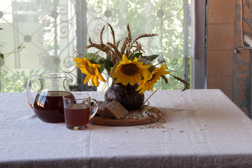 Still-life with kvass (kvas) in a transparent jug and a bouquet