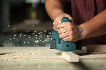 Carpenter working with electric planer. - obrazy, fototapety, plakaty