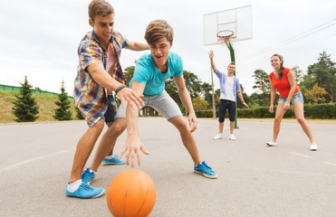 group of happy teenagers playing basketball