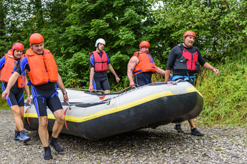 M&auml;nner tragen Schlauchboot zur Rafting-Tour