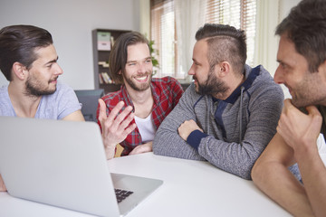 Cheerful men sitting in front of the laptop