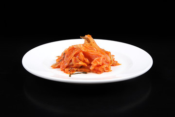 Kimchi on white plate against black background