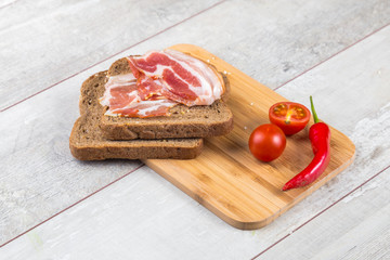 Tomato, toasts, meat and salad on wooden table