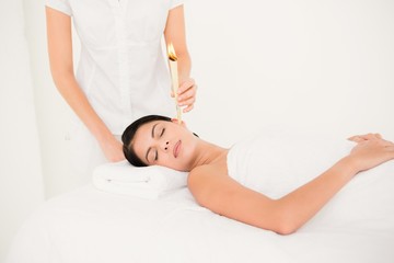 Fototapeta na wymiar Beautiful woman receiving ear candle treatment at spa center