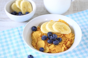 Breakfast cereal with blueberries, bananas and milk on a rustic