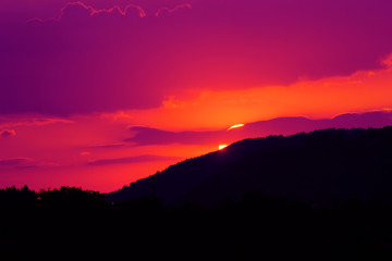 Tramonto viola - il sole che sta tramontando dietro una montagna