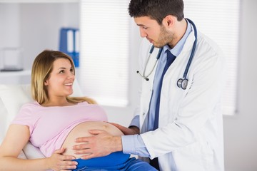 Doctor examining stomach of pregnant patient and giving advice
