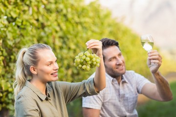 Obraz premium Two young happy vintners holding a glass of wine and grapes