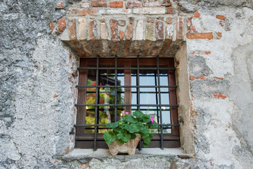 Fototapeta na wymiar Fenêtre dans un mur en pierre avec un géranium en décoration
