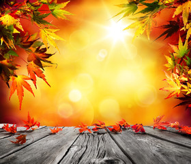 Autumn background with red falling leaves on wooden plank
