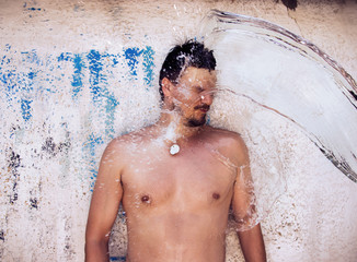 Man Gets Freshed by Water Splash on Grunge Wall Background