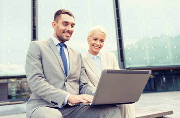 Fototapeta na wymiar smiling businesspeople with laptop outdoors
