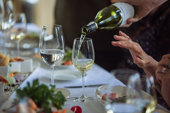 Waiter pouring white wine to senior  in restaurant