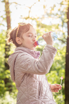 Photo of little girl drinking water with in the park