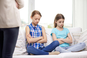upset guilty little girls sitting on sofa at home
