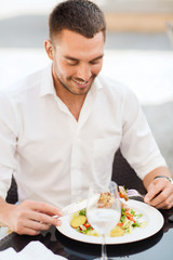 happy man eating salad for dinner at restaurant