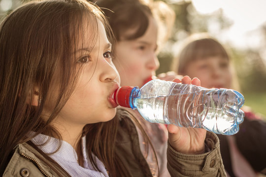 Photo of little girls drinking water from PET bottle