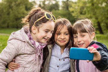 Fototapeta premium Photo of there little girls making selfie in the park