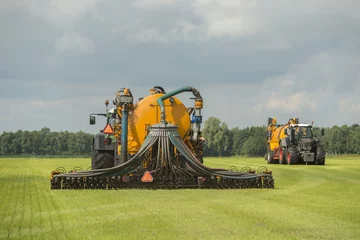 Deurstickers Injecting of liquid manure with two tractors and yellow vulture © TOF