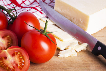 Tomatoes and cheese with knife on chopping board