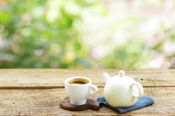 Tea cup with old teapot on wooden table