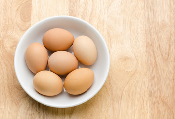 Fresh eggs in the bowl on wooden background
