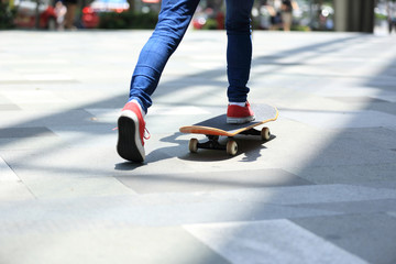 Fototapeta na wymiar young skateboarder legs riding on skateboard on city