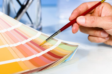 Artist hand pointing to color samples in palette with paintbrush - 88623972