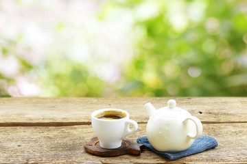 Tea cup with old teapot on wooden table