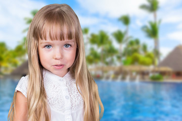 Little blonde girl near the pool in tropical resort